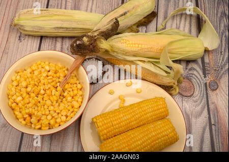 Grains de maïs doux dans une assiette avec une cuillère en bois, le gros sel et les épis de maïs sur la table. Régime alimentaire sain. Régime alimentaire de remise en forme. Pour une petite douceur Banque D'Images