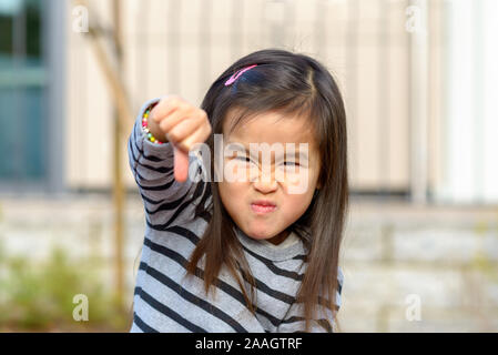 Fille asiatique peu en colère son poing frappe à l'appareil photo tout en tirant une féroce face à un spectacle de l'agression d'enfant Banque D'Images