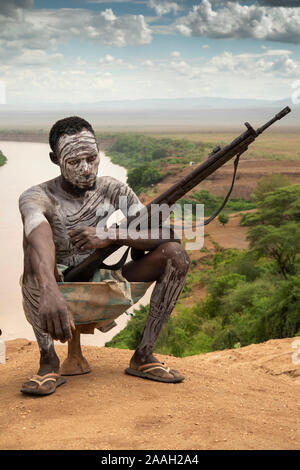 L'Éthiopie, de l'Omo, Kolcho village, l'homme tribal Karo, décorée de boue, avec au-dessus du fleuve Omo Banque D'Images