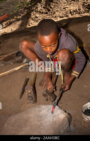 L'Éthiopie, de l'Omo, Jinka, Yenegrew coudre l'AARI village, young blacksmith hammering blade Banque D'Images