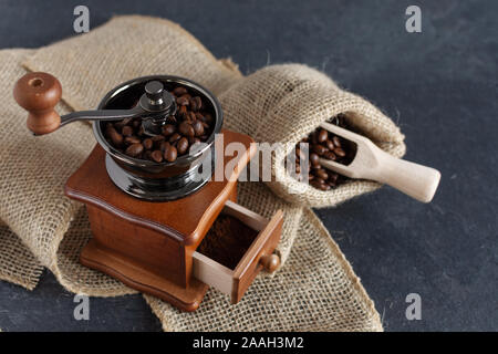 Moulin à café manuel vintage et les grains de café dans un sac de toile sur une table en bois. Copier l'espace. Banque D'Images