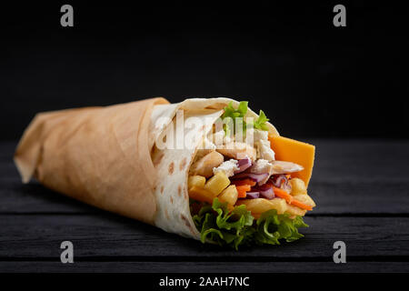 Doner kebabs savoureux avec une salade fraîche et les parures de viande rôti émincé servi en tortillas sur papier brun comme un en-cas à emporter. Banque D'Images