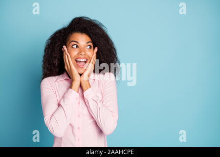 Photo de la peau sombre ondulée incroyable dame holding arms sur les pommettes regarder incroyable vente prix shopping chemise rose d'usure couleur bleu isolé Banque D'Images