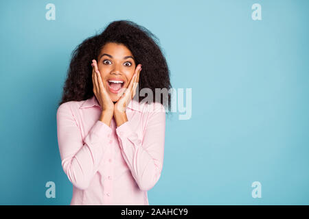 Photo de la peau sombre ondulée incroyable dame holding arms sur les pommettes regarder incroyable vente prix shopping chemise rose d'usure couleur bleu isolé Banque D'Images