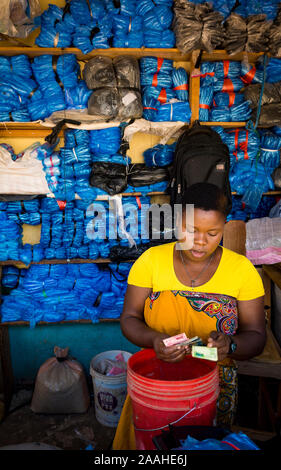 L'argent comptant des femmes dans un marché à Lilongwe, Malawi, la vente des sacs en plastique bleu et noir Banque D'Images