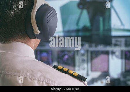 Close up d'épaulettes de capitaine et d'écouteurs dans le cockipt d'avion Banque D'Images