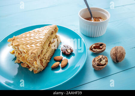 Gâteau avec des arachides, noix, chocolat et crème caramel sur fond bleu en bois. Banque D'Images