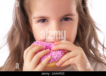 Happy little girl eating donut rose Banque D'Images