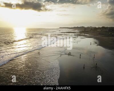 Vue aérienne de la plage volcanique noire, avec des vagues d'exécution dans le coucher du soleil, walker, plage de Canggu, Bali, Indonésie Banque D'Images