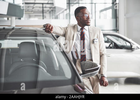 Le jeune homme noir attrayant achète une nouvelle voiture, des rêves venir vrai Banque D'Images