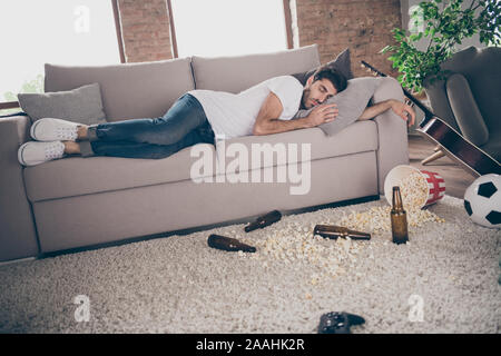 Photo de race mixte boozer guy allongé gueule de couchage canapé bière bouteille popcorn sur plancher avait divertissement folles souffrances après partie matin messy Banque D'Images