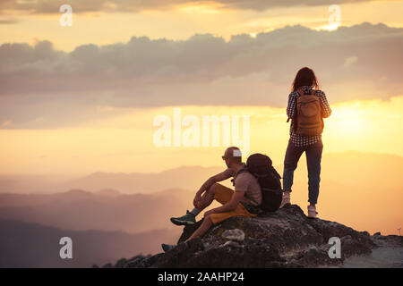 Deux randonneurs avec sacs à dos ont du reste en montagne au coucher du soleil Banque D'Images