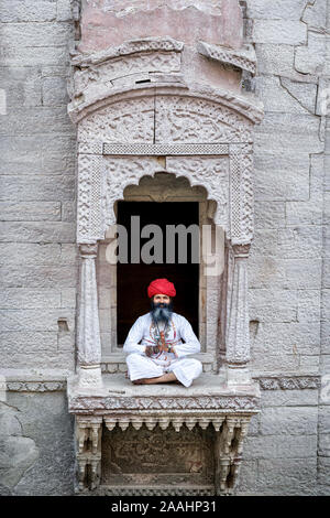 Un homme pratiquant le yoga dans une fenêtre, à la cage d Toorji Jhalra Ka, Jodhpur, Rajasthan, India Banque D'Images