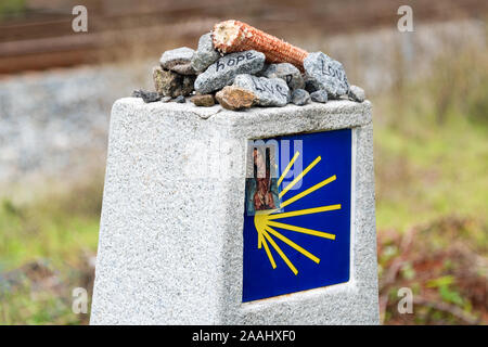 Le jaune coquille Saint-Jacques, symbole touristique du Camino de Santiago direction montrant sur Camino Norte en Espagne.Colonne avec la signature de la façon de roches Banque D'Images