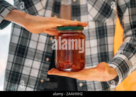 Personne main tenant un pot de confiture faite maison avec des fruits, des pots en verre Banque D'Images