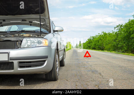 Problèmes avec la voiture et un triangle rouge pour avertir les autres usagers de la route. Banque D'Images
