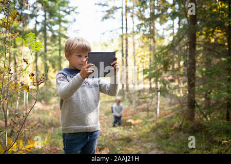 Boy taking photograph of forest, frère suivant derrière Banque D'Images