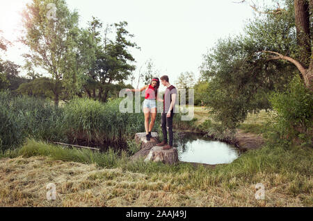 Man helping woman reste sur des bûches en étang, Wilhelminenberg, Vienne, Autriche Banque D'Images