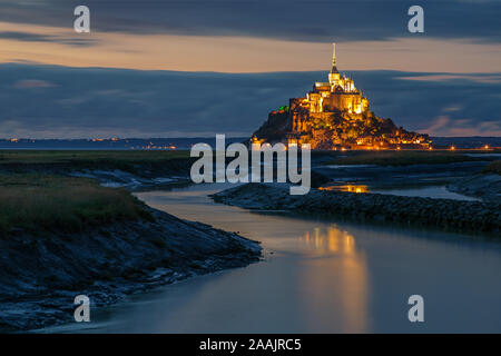 Normandie, France. Le Mont Saint Michel illuminé se reflète sur l'eau Banque D'Images