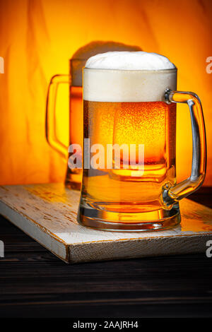 Deux verres avec mousse blanche sur table en bois sombre et fond jaune Banque D'Images
