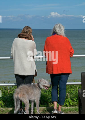Deux dames admirez la vue sur la mer depuis les falaises le long de la North Norfolk pendant que dog walking, Cromer, Norfolk, England, UK Banque D'Images