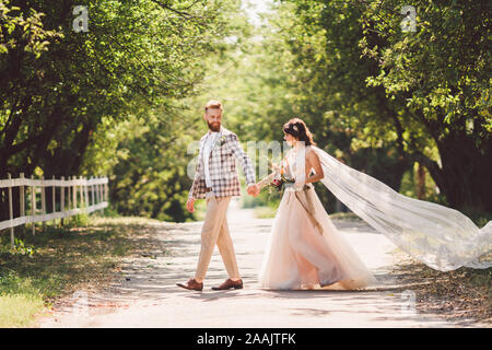 Couple de mariage belle forêt bois. Mariés, suivez-moi, couple marié, femme en robe de mariée blanche et voile. Histoire d'amour à l'extérieur rustique Banque D'Images