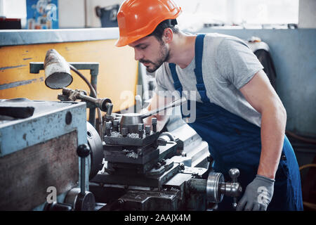 Portrait d'un jeune travailleur dans un casque à une grande usine de recyclage des déchets. L'ingénieur contrôle le travail des machines et autres équipements Banque D'Images