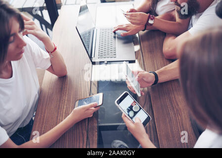 Un groupe de jeunes avec des gadgets et un ordinateur portable organiser une séance de brainstorming et de communiquer les uns avec les autres. Le concept de l'élaboration d'une jeune entreprise Banque D'Images