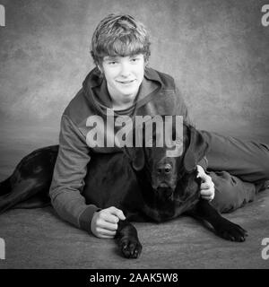 Studio portrait of teenage boy avec Labrador dogue allemand chien mixte Banque D'Images