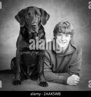 Studio portrait of teenage boy avec Labrador dogue allemand chien mixte Banque D'Images