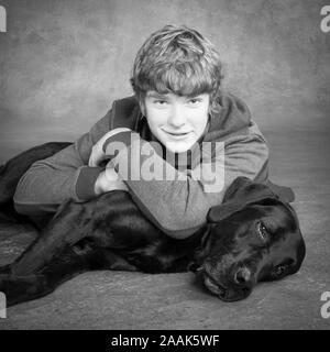 Studio portrait of teenage boy avec Labrador dogue allemand chien mixte Banque D'Images