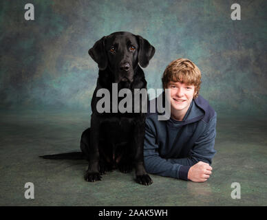 Studio portrait of teenage boy avec Labrador dogue allemand chien mixte Banque D'Images