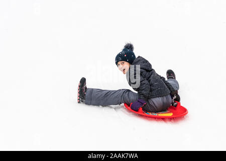 Enfant se déplace en arrière à partir d'une colline sur un bateau de glace rouge Banque D'Images