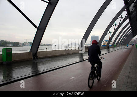 Motion floue image de l'homme monter sur un vélo à l'arrière de la gare principale appelée Amsterdam Centraal. C'est un jour d'été pluvieux. Banque D'Images