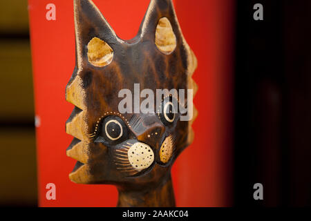 Sculpture en bois d'un chat sur fond rouge foncé Banque D'Images