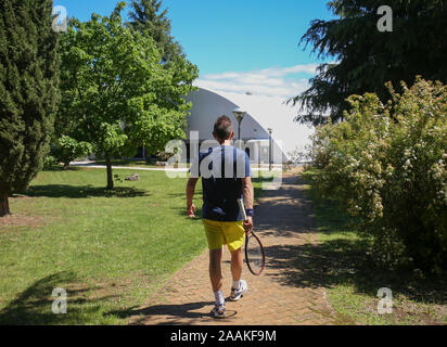 Homme tenant une raquette de tennis sur son chemin à l'intérieur de la salle de tennis. Banque D'Images