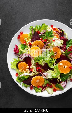 Salade de Noël avec des betteraves, l'oignon rouge, mandarine, Grenade, le persil, les noix de pin et feuilles de laitue Banque D'Images
