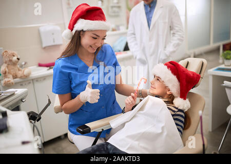 Femme dentiste à Santa hat dent examen jeune patient en ambulant. Banque D'Images