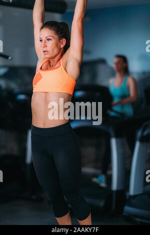 Athlète féminin faisant tirer-se lève dans la salle de sport. Banque D'Images