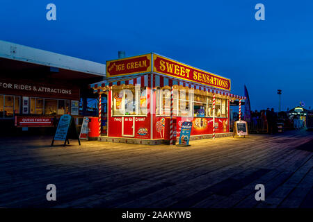 Temps de nuit vue vue de la crème glacée et confiseries boutique sur Clacton Pier, Clacton On Sea. Banque D'Images