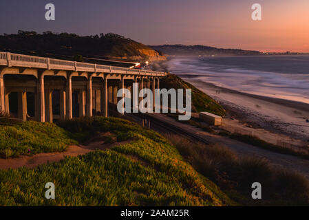 Torrey Pines Road sur le pont, des voies de chemin de fer située au-dessous, à côté de plage de sable avec des vagues se brisant sur la plage au coucher du soleil, La Jolla, Californie, USA Banque D'Images