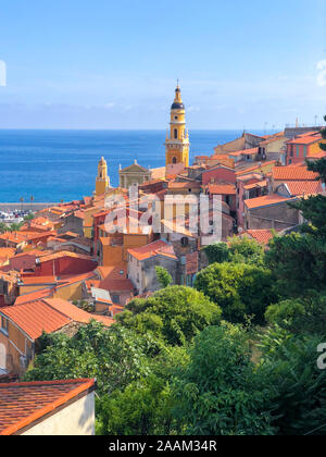Paysage ensoleillé du vieux centre-ville de Menton, au-dessus de la basilique Saint Michel debout et la mer en premier plan Banque D'Images