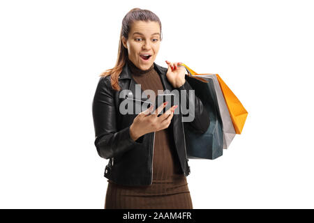 Surprised young woman with shopping bags en regardant son téléphone portable isolé sur fond blanc Banque D'Images