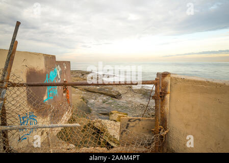 Vue côtière de derrière un mur et vieille clôture. San Diego, Californie, USA. Situé dans l'océan plage communauté de San Diego. Banque D'Images