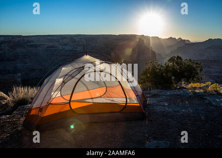 Un réveil au lever du soleil sur camping avec tente orange près du bord d'un grand canyon dans le désert de San Rafael Swell dans Centre de l'Utah Banque D'Images