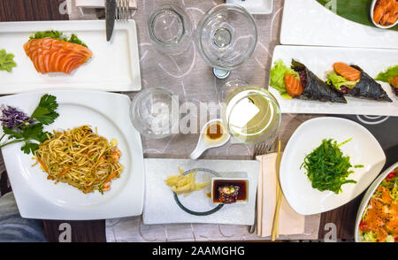 La cuisine japonaise sur une table pleine de délicieux plats. Le saumon frais, le riz sushi Temaki cônes, crevettes, algues spaghetti avec sauce soja, salade de surimi Banque D'Images