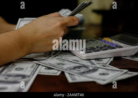 Femmes Hommes d'argent comptant sur une pile de billets de 100 dollars américains, beaucoup d'argent Banque D'Images