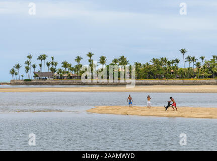 Un homme et sa famille de jouer avec leur chien sur une plage de sable. Porto Seguro, Bahia, Brésil, Amérique du Sud. Banque D'Images