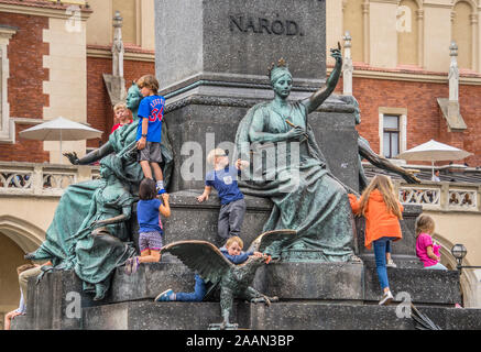 Enfants frollicking parmi les figures allégoriques, à la base de l'Adam Mickiewicz Monument sur la place principale de Cracovie, à côté de la célèbre halle aux draps, Banque D'Images