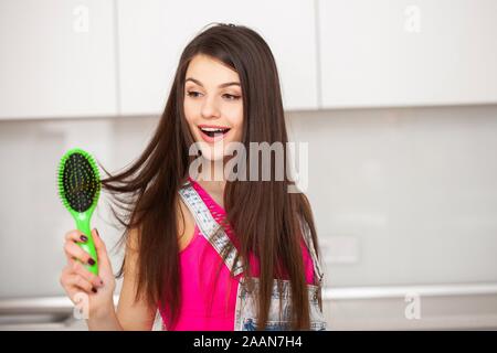 Girl est titulaire d'une brosse sans cheveux et souriant Banque D'Images